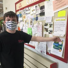 Student hangs COVID information flyer on bulletin board