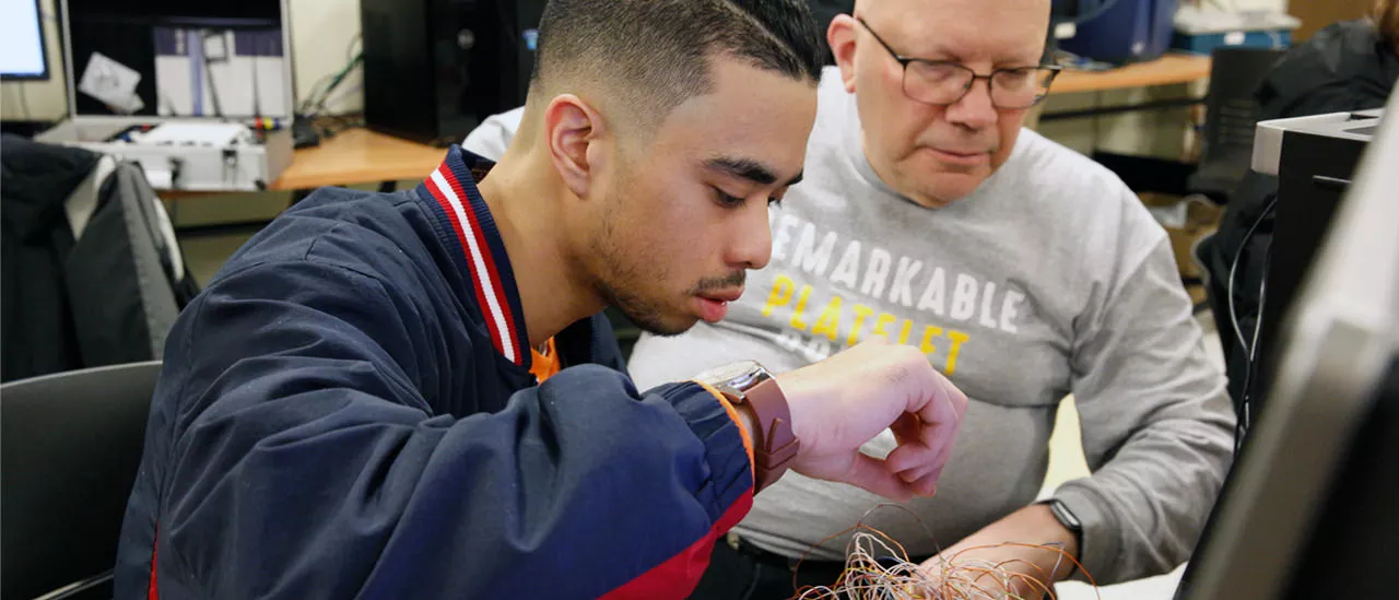 Student and faculty member working together on wiring a computer.