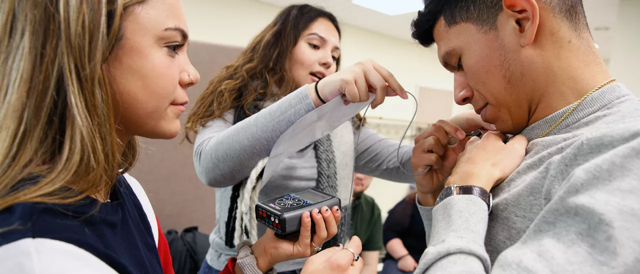 Students hooking up a virtual reality device to another student for research.